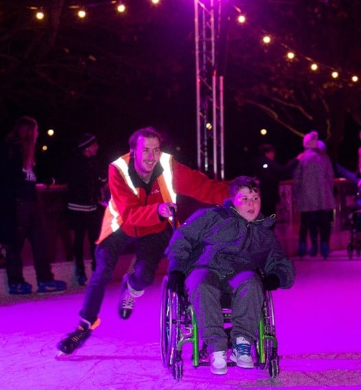 Wheelchair user enjoying a relaxed ice skating session with support
